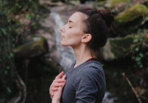 Žena radi vežbe disanja za opuštanje u prirodi