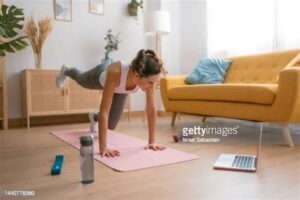 Žena vežba plank kod kuće na prostirci u dnevnoj sobi